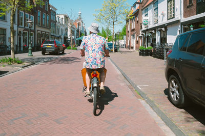 Rear view of man riding bicycle on street