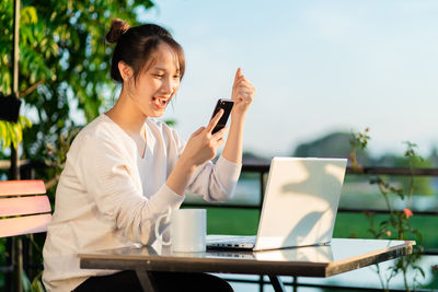 Young woman using mobile phone while sitting at cafe