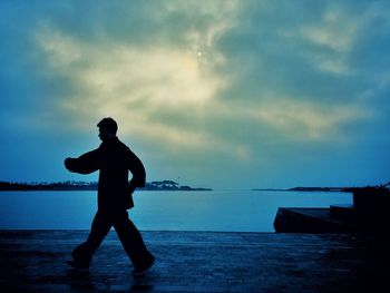 Silhouette man walking on calm beach