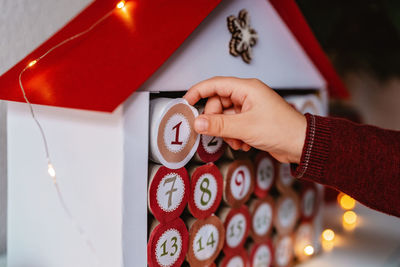 Close up of child hand opening first gift in handmade advent calendar. sustainable christmas