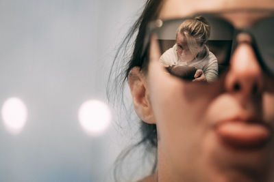 Close-up of woman wearing sunglasses with female friend photographing at home