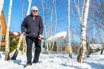 Full length of a man working with shovel while standing on snow covered land