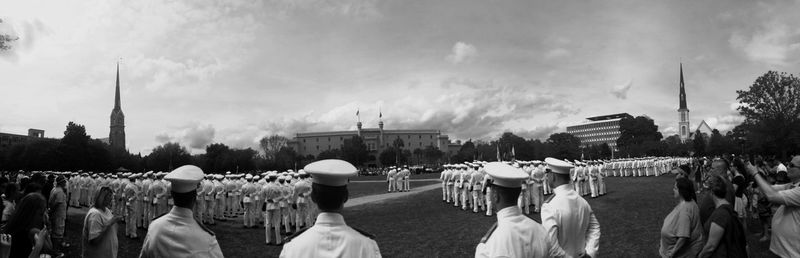 People walking on city street against cloudy sky
