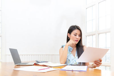 Young woman using mobile phone while sitting on table