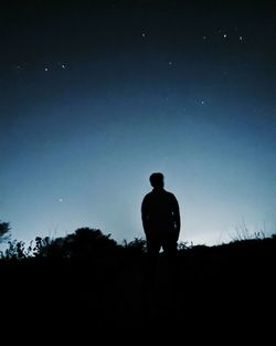 Silhouette man standing on field against clear sky at night