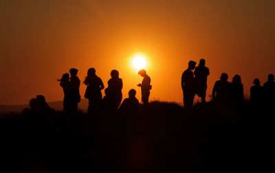 Silhouette people standing against sky during sunset