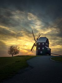 Windmill on field against sky during sunset