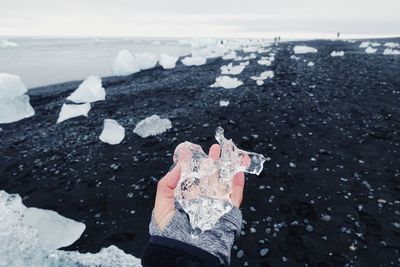 Human hand on frozen sea shore