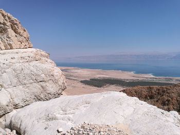 Rock formations by sea against clear blue sky