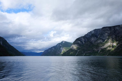 Scenic view of lake and mountains against cloudy sky