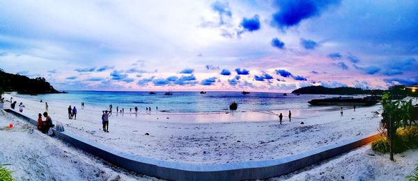 Panoramic view of people on beach against sky