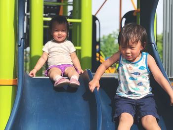 Cute boy sitting on slide at playground
