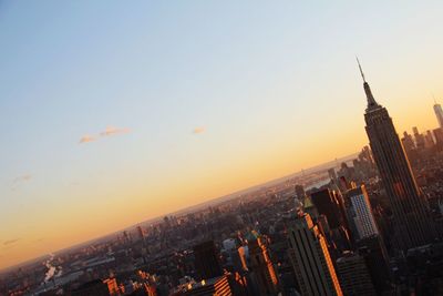 Empire state building with cityscape against sky during sunset