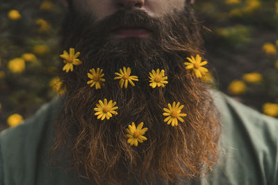 Yellow flowers arranged on man's brown beard