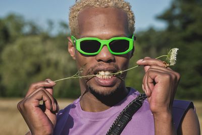 Portrait of man holding flowering plant standing outdoors