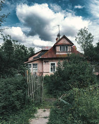 House amidst trees and buildings against sky
