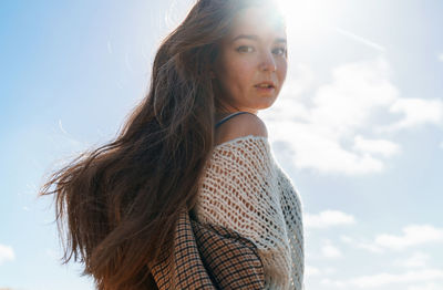 Portrait of beautiful woman standing against sky