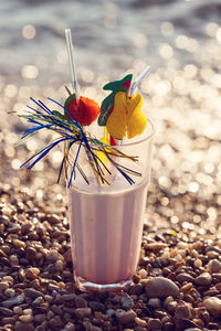 Glass of alcoholic cocktail standing in the sand on a tropical beach at sunset in the evening