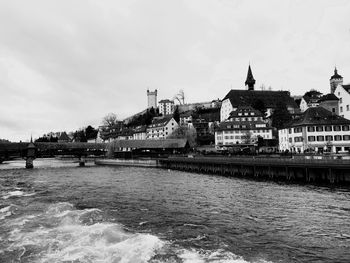 Bridge over river by buildings against sky in city