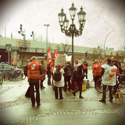 People on footpath in city against sky