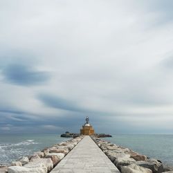 Lighthouse by sea against sky