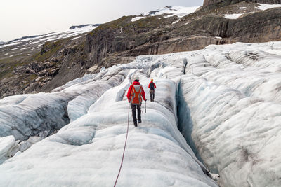 Rear view of people walking on glacier