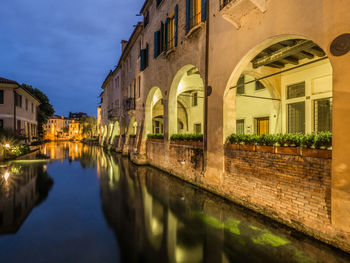 Canal amidst buildings against sky at night