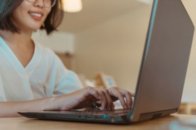 Midsection of woman using laptop while sitting on table