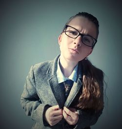 Close-up portrait of young woman wearing blazer by wall