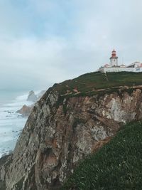 Lighthouse by sea against sky