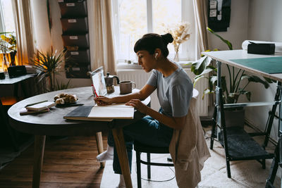 Side view of female business professional planning strategy with colleague on video call through laptop at home office