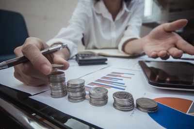 Midsection of businesswoman stacking coins at desk in office