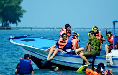 People enjoying in sea against clear blue sky