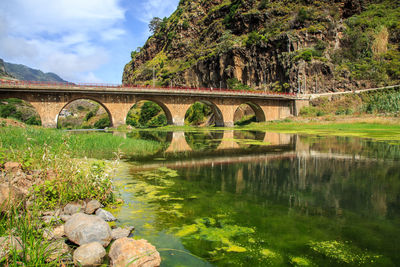 Arch bridge over river against sky