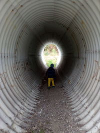 Rear view of woman standing in tunnel