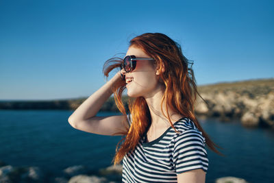 Young woman wearing sunglasses against sea against sky