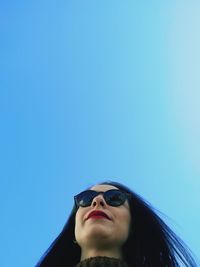 Portrait of beautiful young woman against clear blue sky