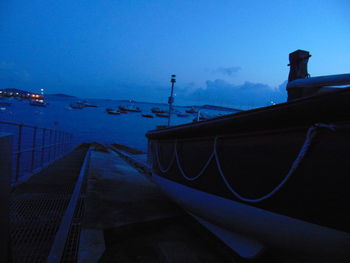 Sailboats moored on sea against clear blue sky at dusk