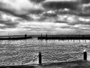 Pier on sea against cloudy sky
