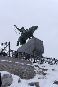 Low angle view of statue against sky during winter