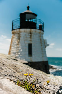 Lighthouse by sea against sky