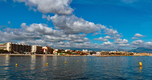 Buildings by sea against blue sky