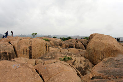 People on rock formations against sky