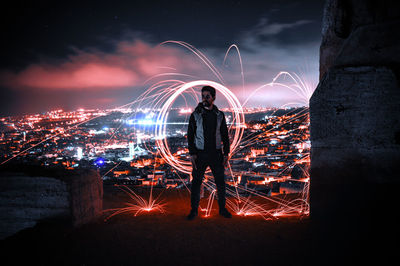 Man looking away standing against illuminated wire wool at night