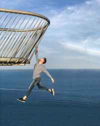 Full length of man hanging on railing against sea
