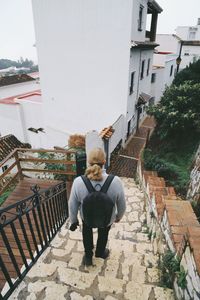 Rear view of man standing on staircase of building