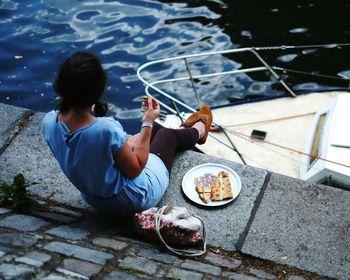 High angle view of woman eating pizza on promenade by river
