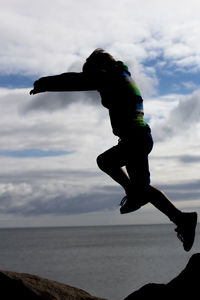 Man jumping in sea against sky