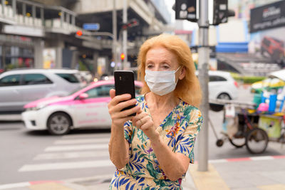 Portrait of woman holding smart phone on street