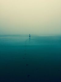 Mid distance of boy running at beach against sky